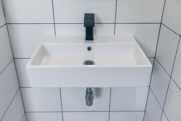 Black bathroom faucet and white square sink..Modern minimalist bathroom design.