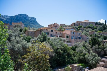 Obraz premium Picturesque Mediterranean village with stone houses nestled in lush greenery under a clear blue sky