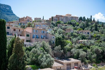 Obraz premium View of a hillside village with stone houses surrounded by lush greenery under a clear blue sky