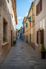 Narrow, picturesque street in a historic town with stone buildings and colorful shutters in Alcudia