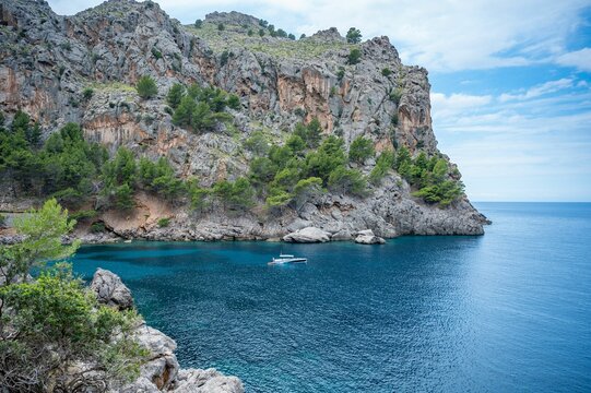 Rocky coastline with boat in clear blue water - Powered by Adobe