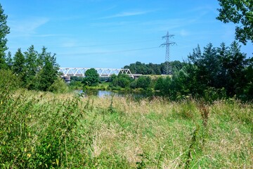 Fototapeta premium Scenic view of a grassy field with a bridge and power lines.