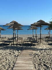Serene beach scene with sun loungers and straw umbrellas.