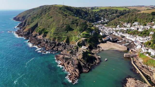 Aerial view over the coastal Polperro village, with seafront houses on a cliff surrounded by nature