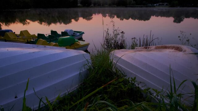 Timelapse of paddleboats moored on the shore of Porstendorf lake at sunrise in Germany