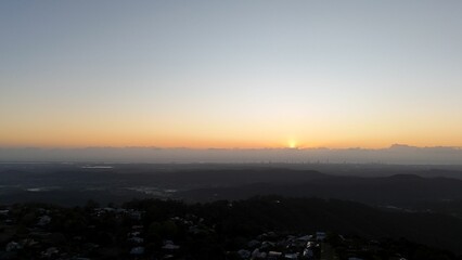 Sunrise over cityscape with clear sky and mountains.