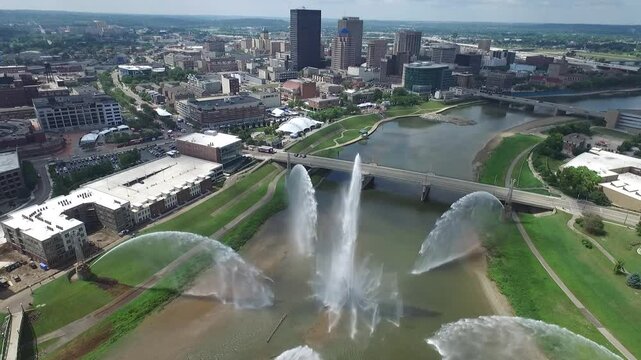 Riverscape MetroPark's fountains in front of downtown skyline of Dayton city, on summer day in Ohio