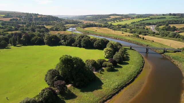 Aerial view over the River Taw with bridges in vast, lush, green fields on a sunny day in Barnstaple