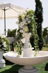Elegant floral arrangement with white roses and greenery in a decorative outdoor setting