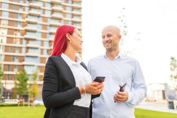 Business people having informal meeting using smartphones outdoors