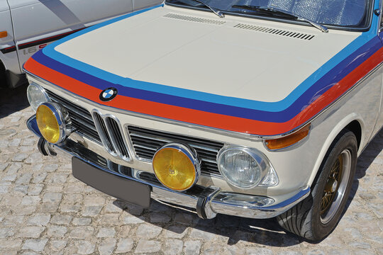 Front view of a restored white bmw 2002 parked on cobblestones