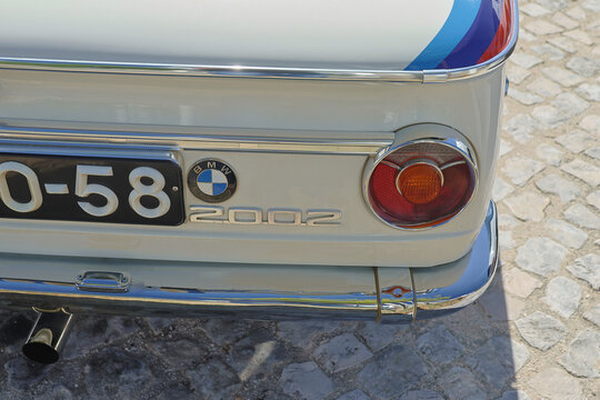 Bmw 2002 taillight and chrome bumper close up parked on cobblestone