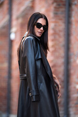 Beautiful woman wearing long leather coat, walking on the street