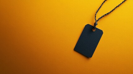 Fototapeta premium Black price tag on vivid orange background, highlighting the contrast between textures in a minimalist retail setting