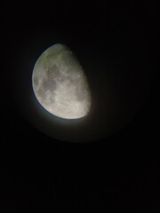 Luna creciente, vista parcial, en sombra, con halo alrededor se aprecian los mares y cráteres. hecha con cámara móvil a través de telescopio