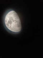 Luna creciente, vista parcial, en luz con halo alrededor se aprecian los mares y cráteres. Foto tomada a través de telescopio