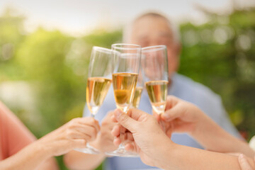 A group of people clink champagne glasses together in a celebratory toast. The image conveys joy, celebration, and togetherness in an outdoor setting, symbolizing special moments and shared happiness.