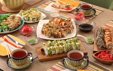 Sushi sets, sauce, wasabi, tea on party table. Food and traditional Asian cuisine. Table setting. 