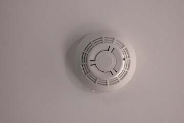 A white smoke detector is sitting on a wall
