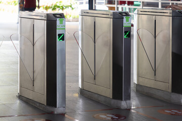 Three metal gates with green lights and a green sign that says 