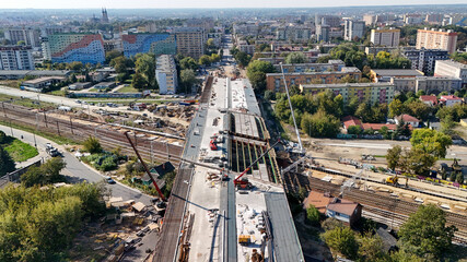 An aerial view of a bustling construction site in an urban setting. Cranes and heavy machinery work to build a new infrastructure, transforming the city skyline. Perfect for urban development