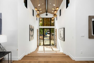 Modern interior hallway with wooden floor, hanging lights, and abstract art on walls