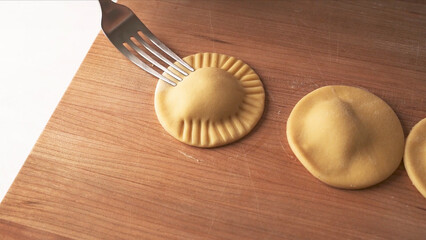 Making Ravioli on the wooden table and fork. 