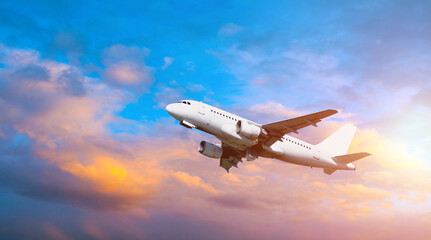 Airplane flying in the sunset sky - travel background with flying airplane with blank livery
