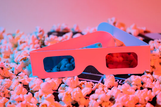 Close up of red and blue 3d glasses on popcorn and a black and white wooden clapperboard, entertainment and cinema concept