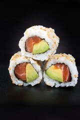 close up sushi roll . group of maki avocado salmon isolated on black background 