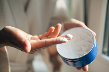 Mature woman is applying a hand cream in bathroom, close-up cropped shot. Morning beauty treatment...