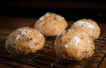 Four classic farm country bread buns on a grill. These homemade rustic rolls balls are made of organic wholemeal multigrain wheat flour for a sourdough recipe.