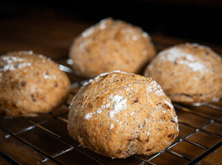 Four classic farm country bread buns on a grill. These homemade rustic rolls balls are made of organic wholemeal multigrain wheat flour for a sourdough recipe.