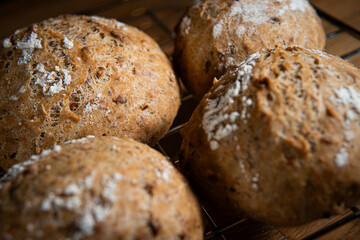 Four classic farm country bread buns on a grill. These homemade rustic rolls balls are made of organic wholemeal multigrain wheat flour for a sourdough recipe.