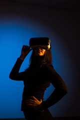 A woman enjoys the world of virtual reality in VR glasses. Virtual reality headset. Artificial intelligence. VR glasses concept. Vertical photo