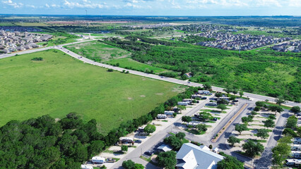 RV trailer park mobile homes near large green vacant land meadow in master planned community outside San Antonio, Texas, new development suburban houses along Rueckle Road, New Braunfels, aerial