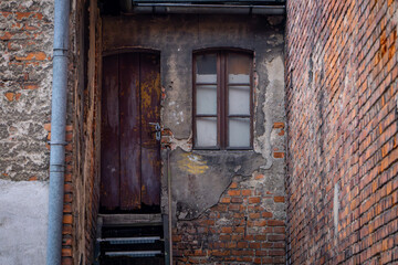 entrance door and window in an old, neglected tenement house in the city center. neglected and ruined buildings.