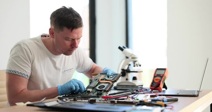 Technical support updates part and repairs laptop. Computer repair concept male engineer testing computer board