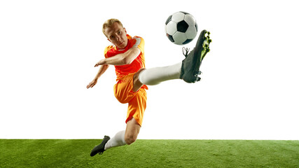 Naklejka premium Young male football player in mid-air kick with full focus on ball. Dynamic shot captures energy of game. Championship. Concept of competition, sport games, movement, energy. Ad.