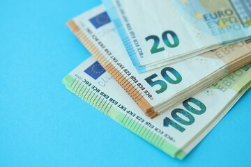 Big amount of one hundred, twenty and fifty euro money bills on blue background