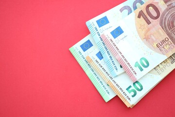 Big amount of one hundred, twenty, ten and fifty euro money bills on red background