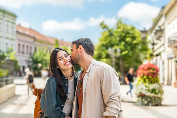 Fototapeta premium Young happy couple in love exchanging looks in the city street. Man and woman, people in relationship outdoor. Modern alternative carefree couple travelers and tourists vacation destination.