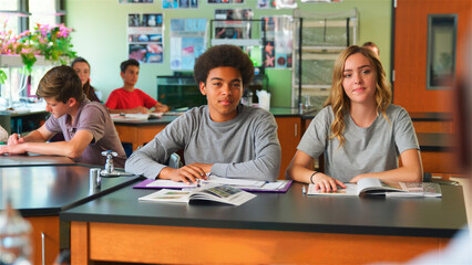 Portrait Of Male And Female High School Students Sitting At Desk In Biology Class