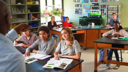 Obraz premium High School Pupils Raising Hands In Biology Class To Answer Question