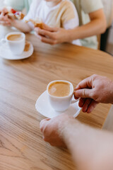 Hands serving fresh coffee at breakfast with a child enjoying croissants, a cozy start to the day