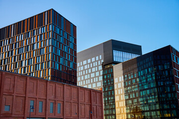 Modern glass office buildings reflecting city skyline in windows at sunset. Contemporary architectural design