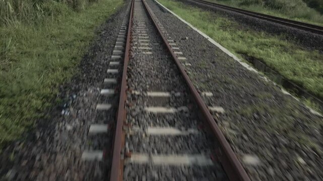 Drone video passes over train tracks in the countryside and the drone flies low, the drone moves straight and the camera faces forward