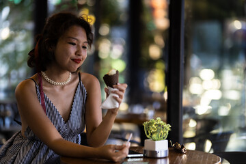Young woman enjoying an ice cream cone at a cozy cafe, feeling relaxed and content on a sunny day.