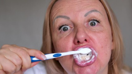 adult woman looking at camera making faces wide eyes sloppy brushing teeth