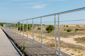 Fototapeta premium Metal barrier in front of a sand dune on a beautiful summer day